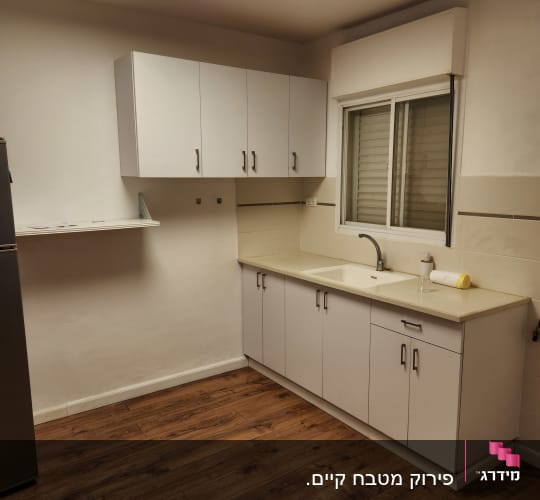 מטבח משופץ עם ארונות לבנים ורצפת עץ חדשה